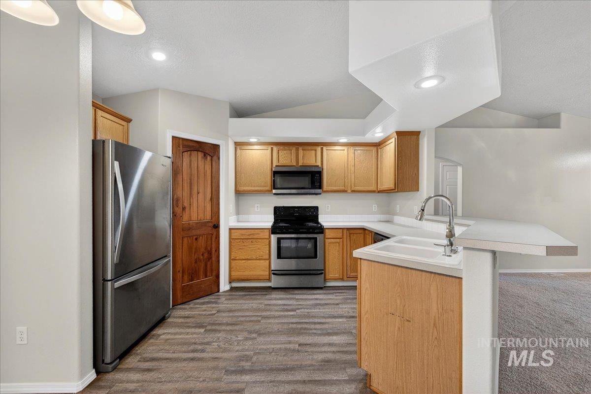 Kitchen featuring light countertops, a peninsula, stainless steel appliances, recessed lighting, and a breakfast bar area
