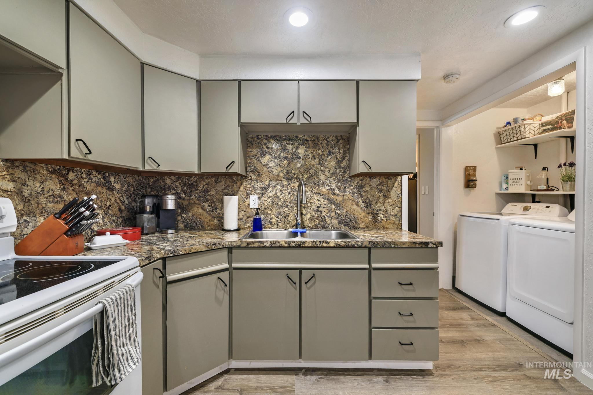 Kitchen with gray cabinets, white range with electric stovetop, light wood-type flooring, washer and clothes dryer, and recessed lighting