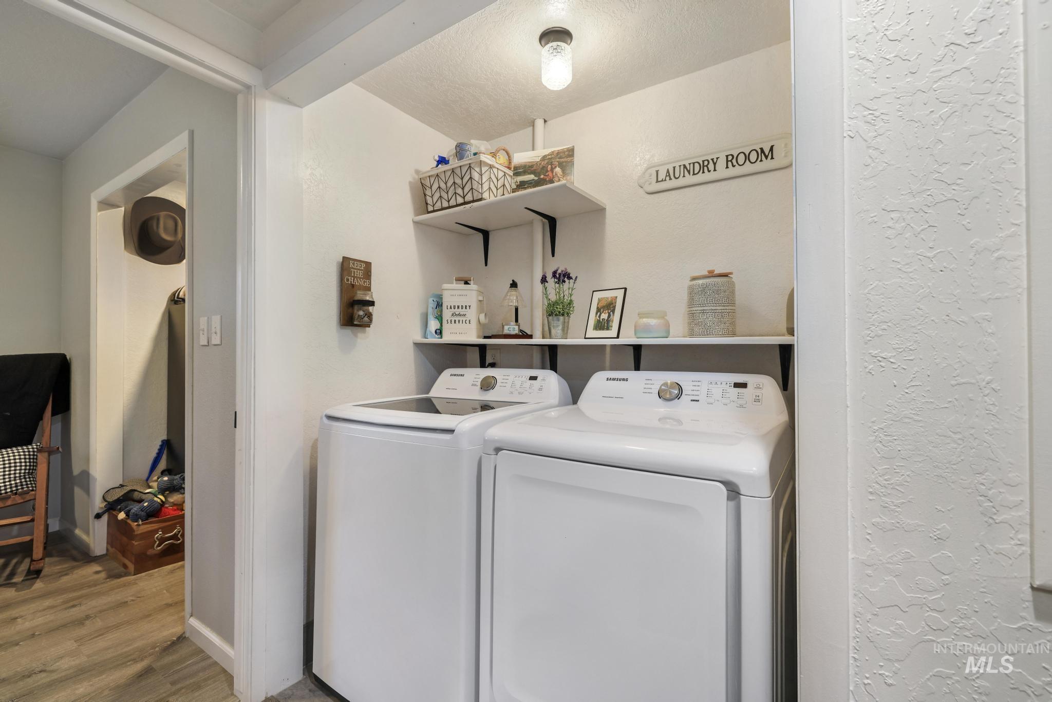 Washroom featuring washer and dryer, wood finished floors, a textured wall, and a textured ceiling