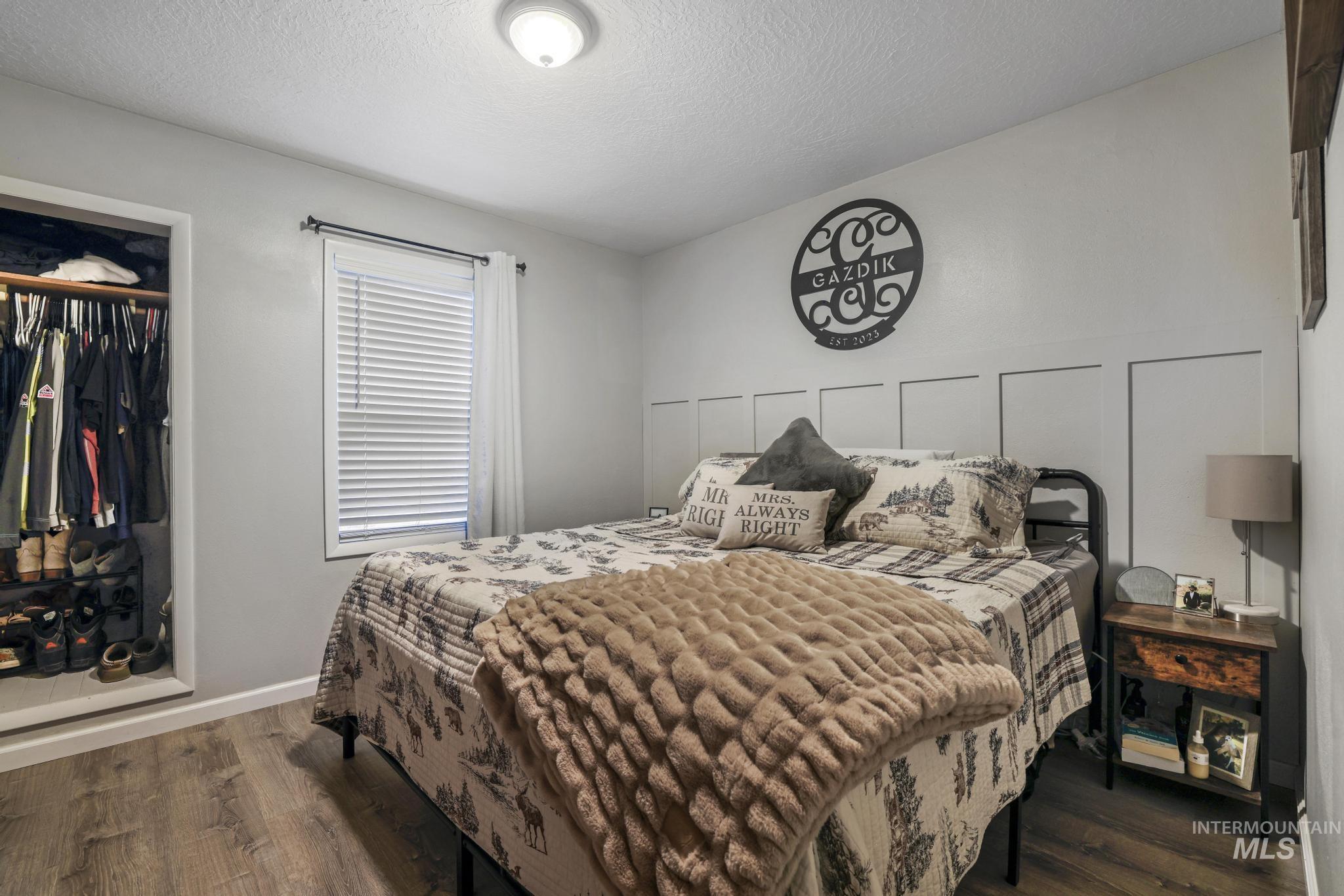Bedroom featuring dark wood-style flooring, a textured ceiling, and a closet