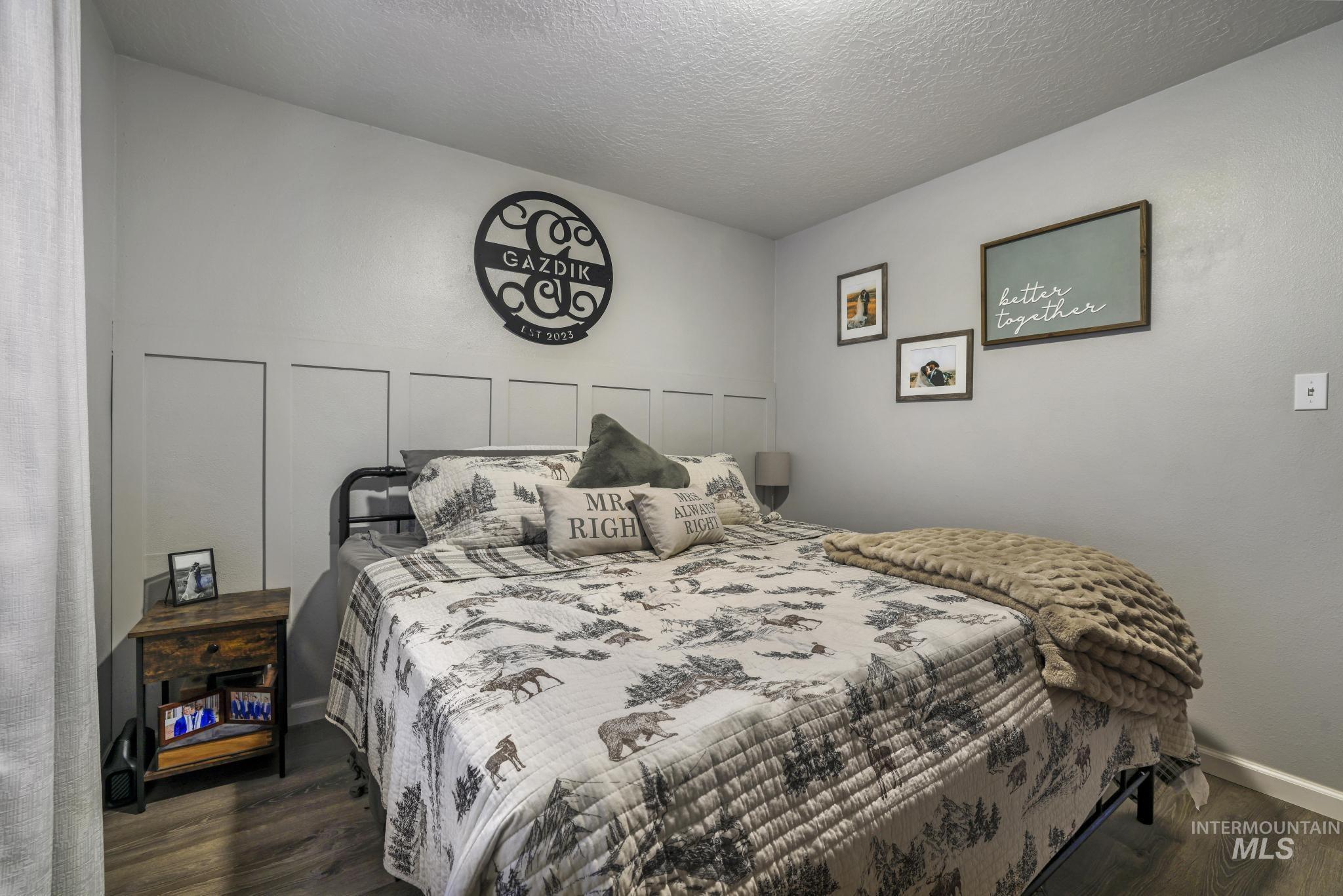 Bedroom featuring a textured ceiling, dark wood-style floors, and a decorative wall