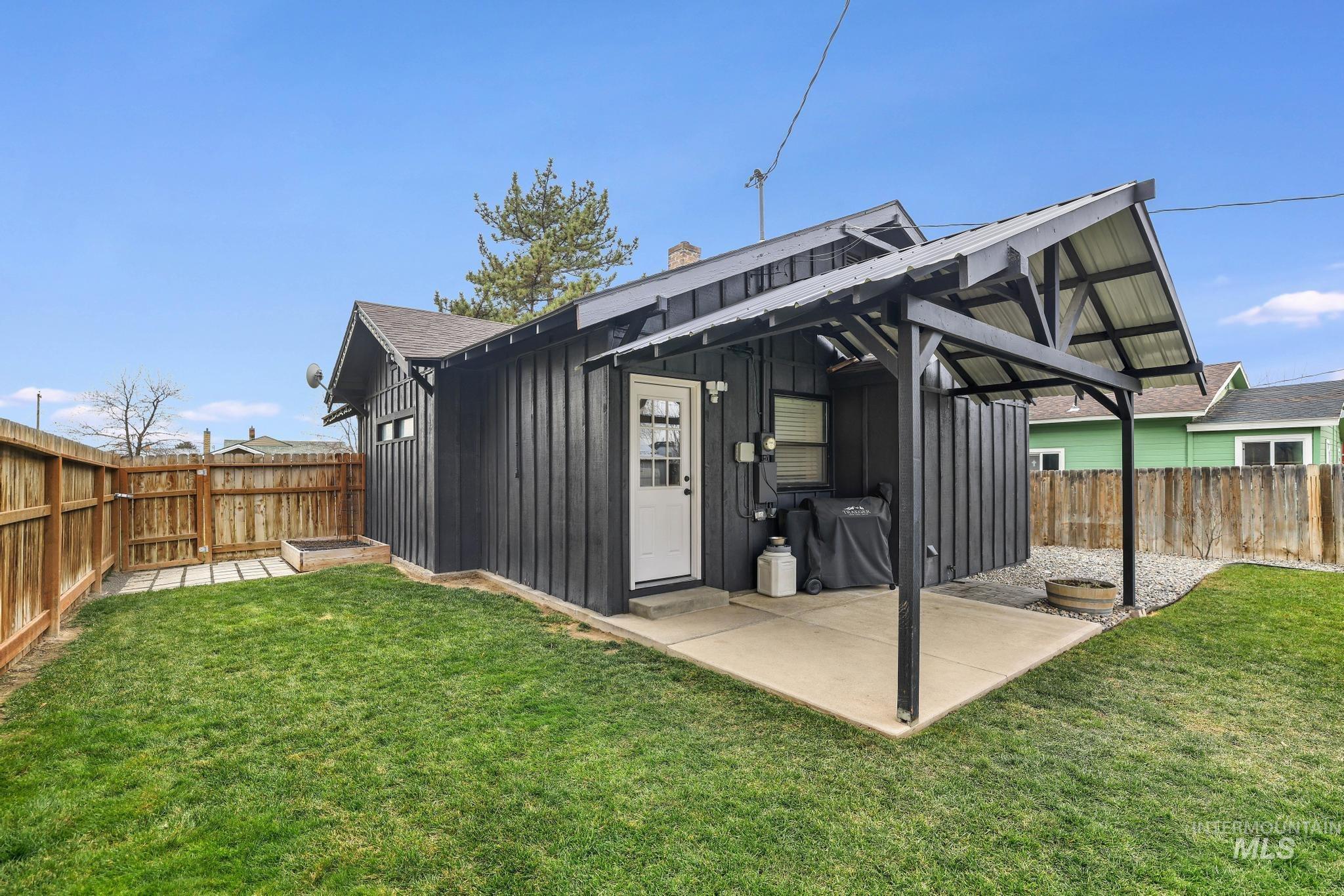 Rear view of property with board and batten siding, a fenced backyard, a patio, a chimney, and roof with shingles
