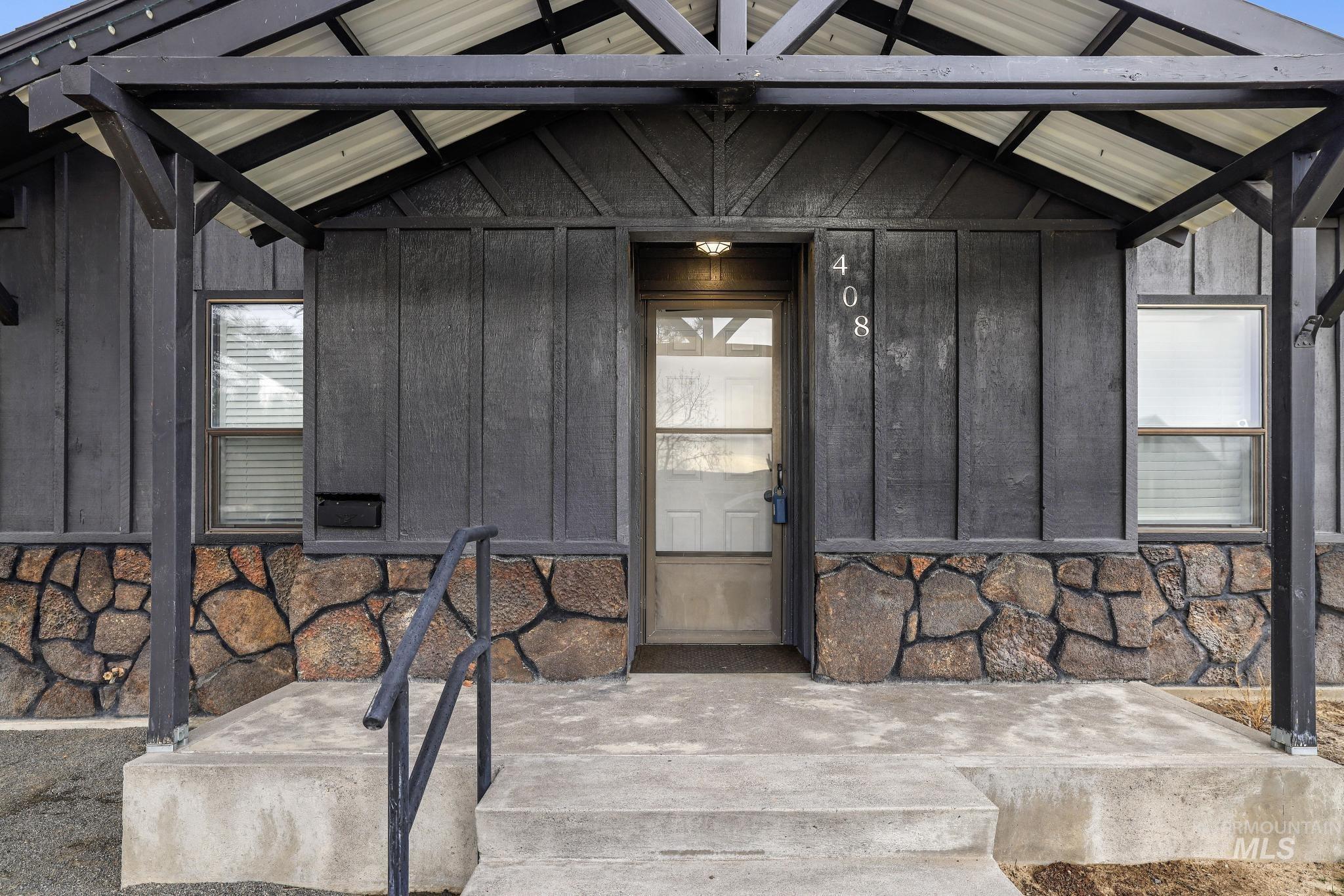 Doorway to property with board and batten siding and stone siding