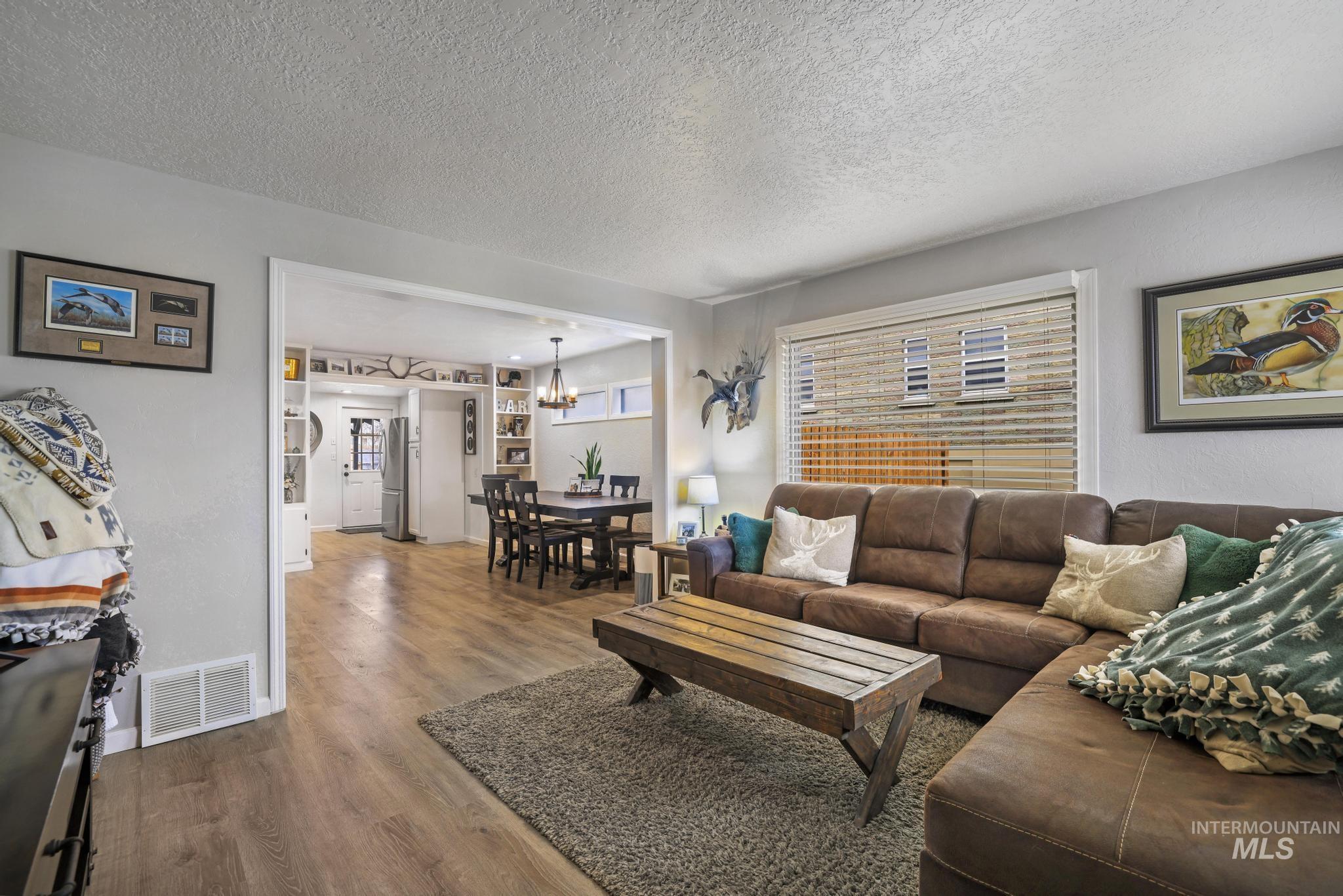 Living room with wood finished floors, a textured ceiling, and a chandelier