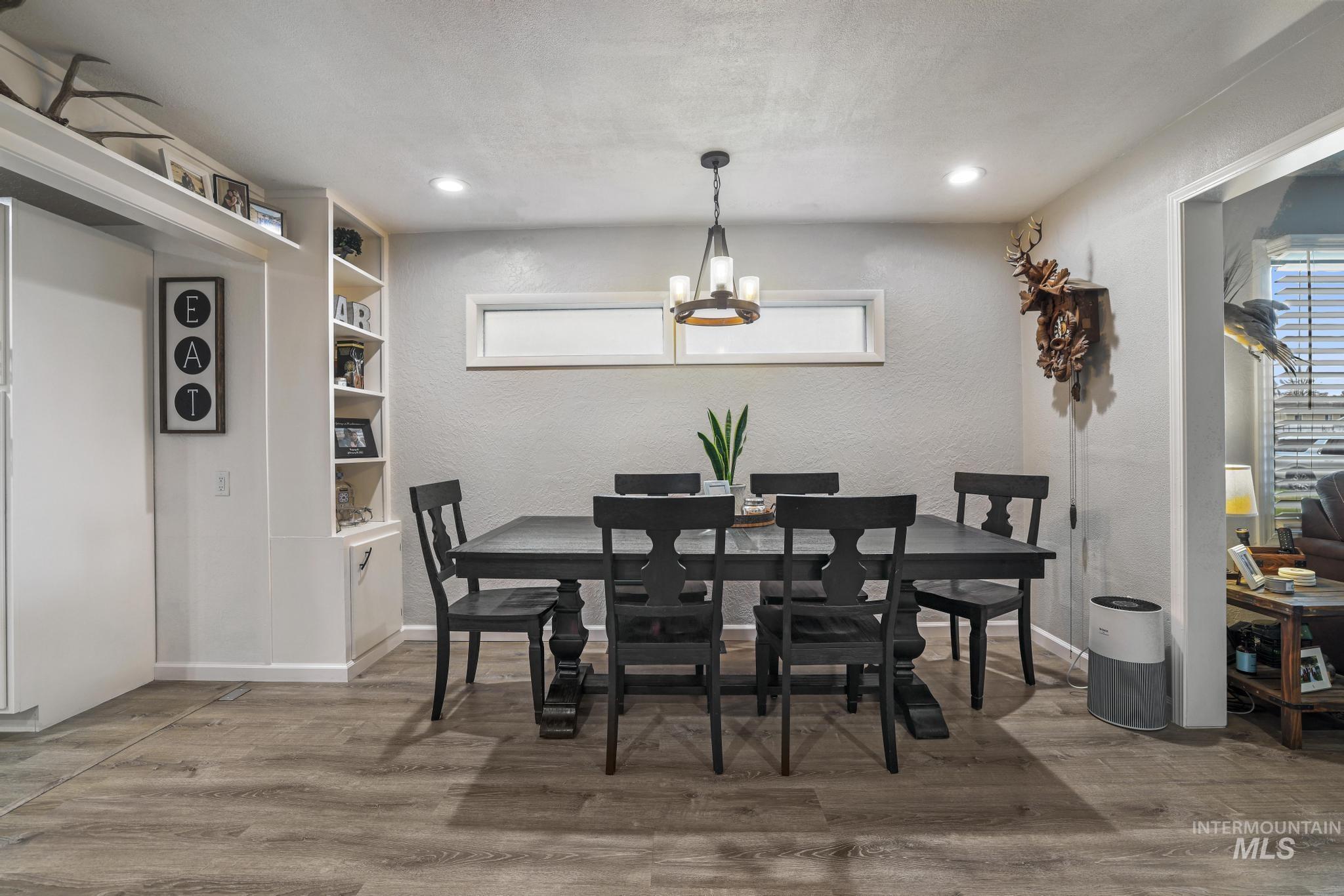 Dining room with light wood-style floors, a textured wall, a chandelier, and plenty of natural light