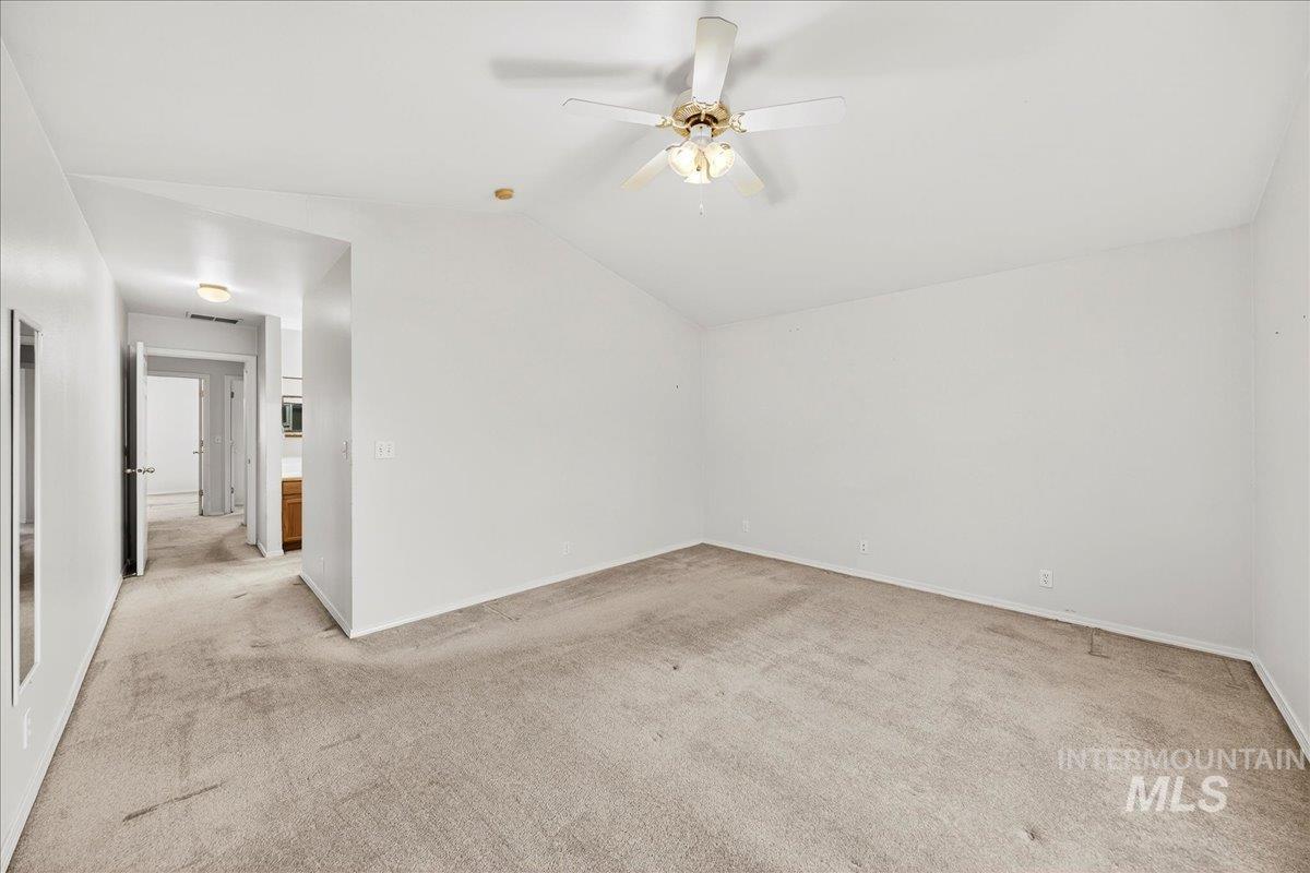 Additional living space with lofted ceiling, light carpet, and a ceiling fan