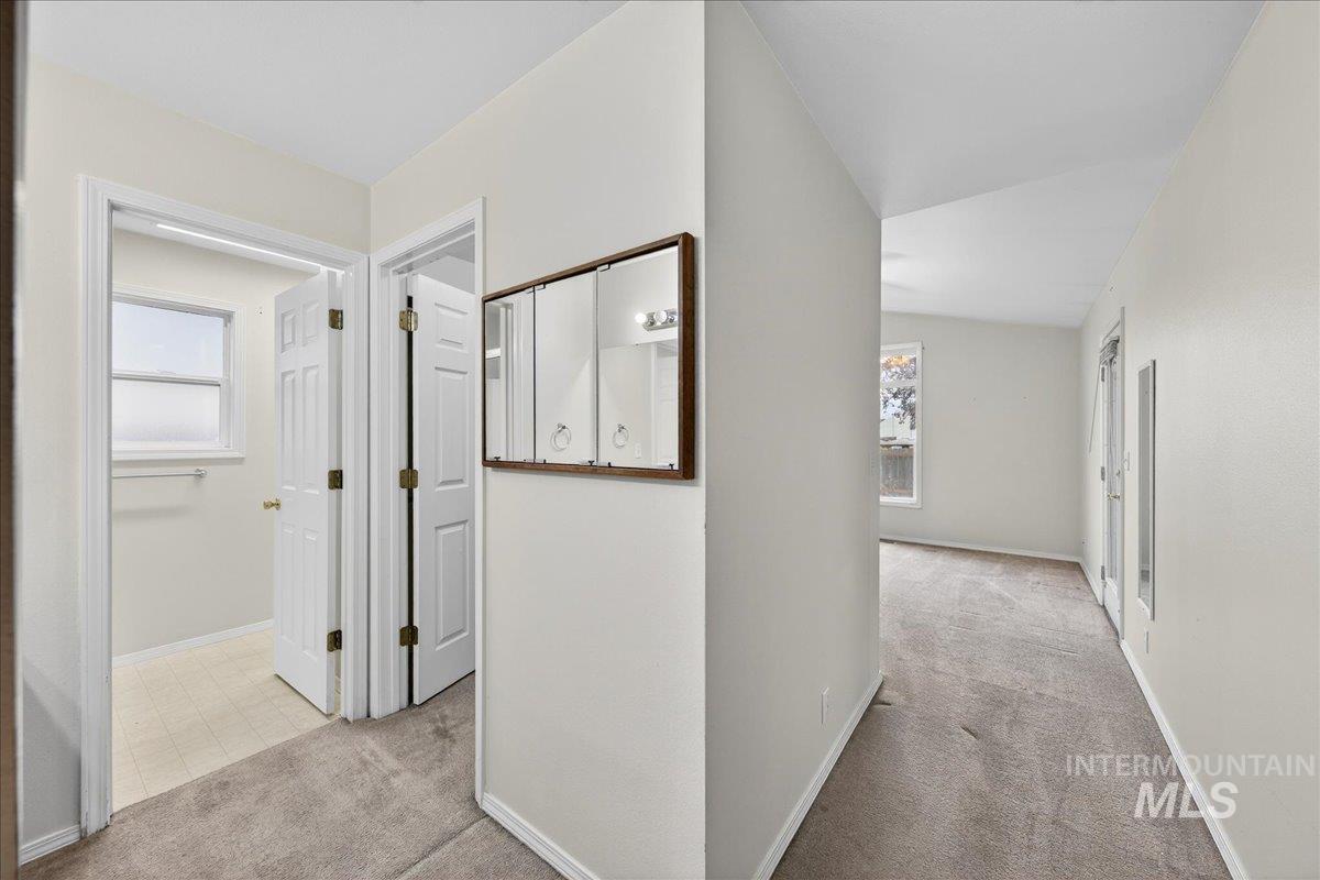 Hallway featuring light colored carpet, plenty of natural light, and lofted ceiling
