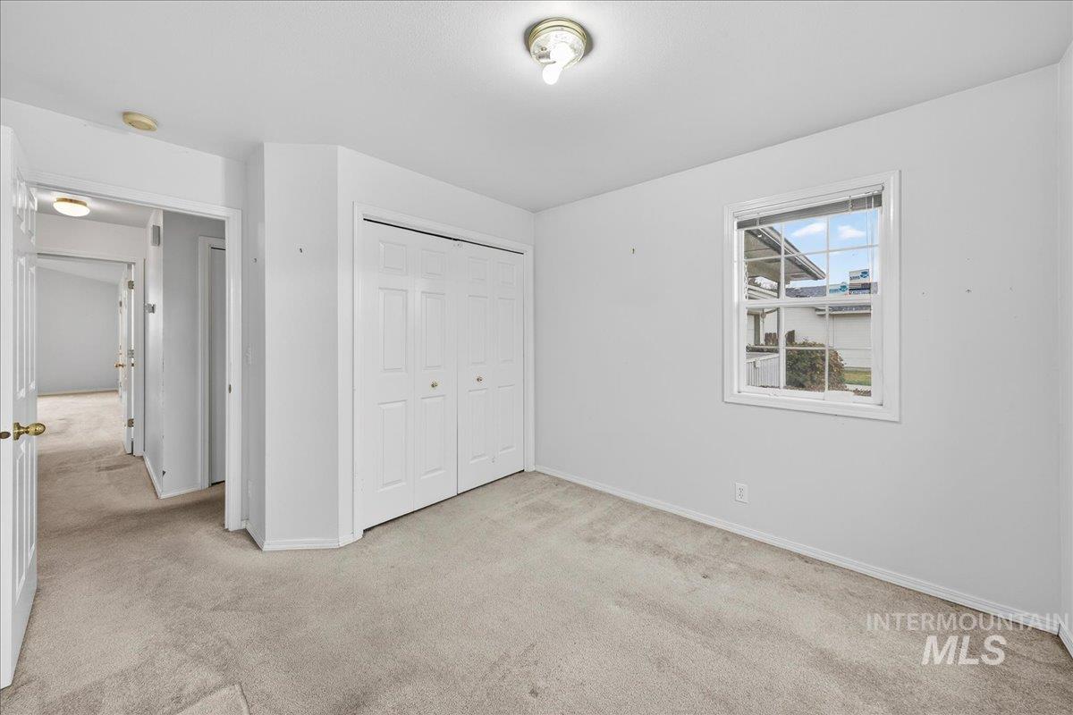 Unfurnished bedroom with light carpet and a closet