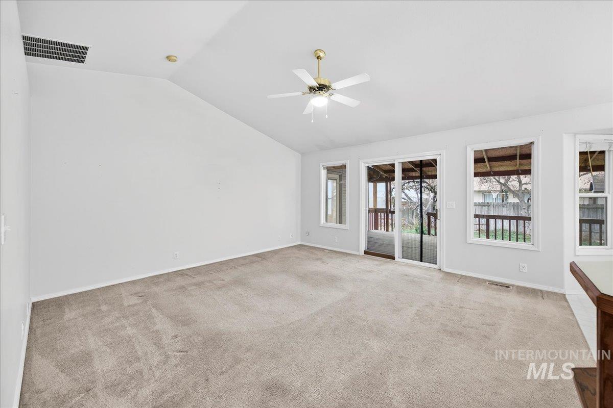 Unfurnished room featuring lofted ceiling, light carpet, and a ceiling fan
