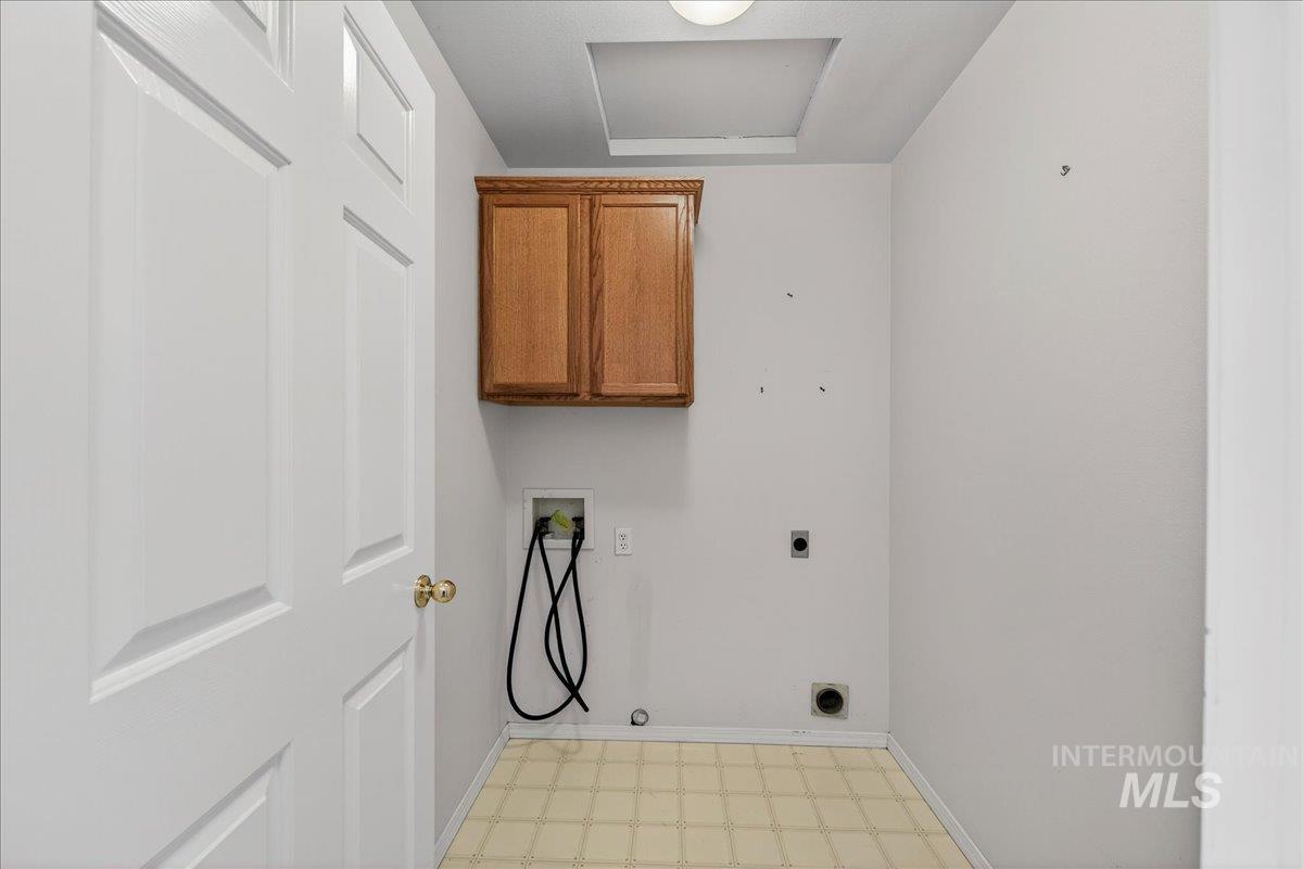 Washroom with light flooring, cabinet space, hookup for a washing machine, hookup for an electric dryer, and attic access