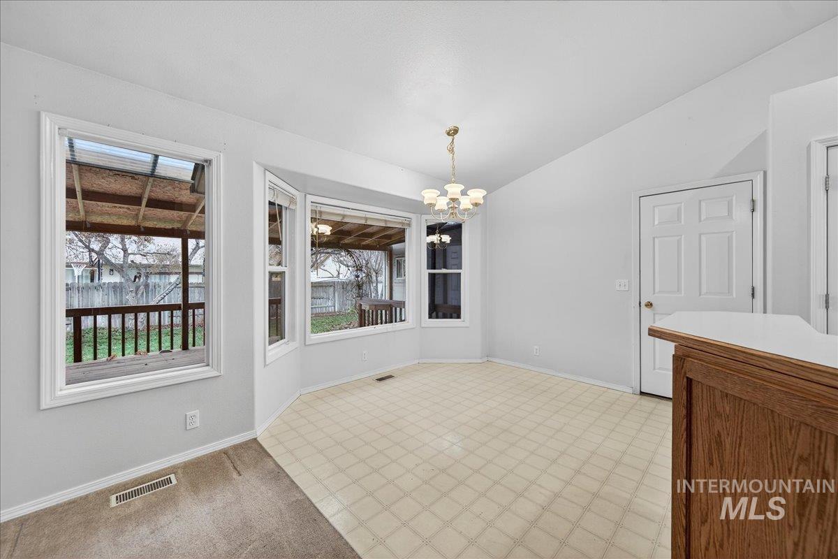 Unfurnished dining area featuring vaulted ceiling, a chandelier, and light floors
