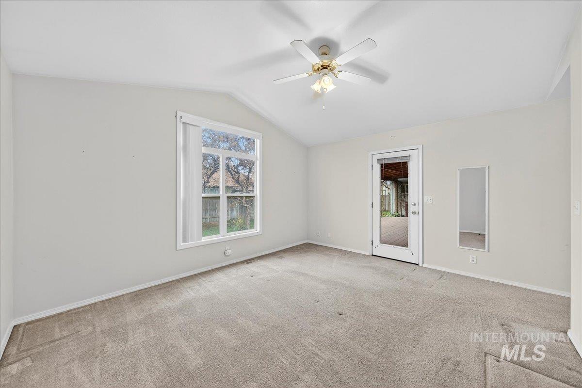 Spare room with lofted ceiling, light carpet, and a ceiling fan