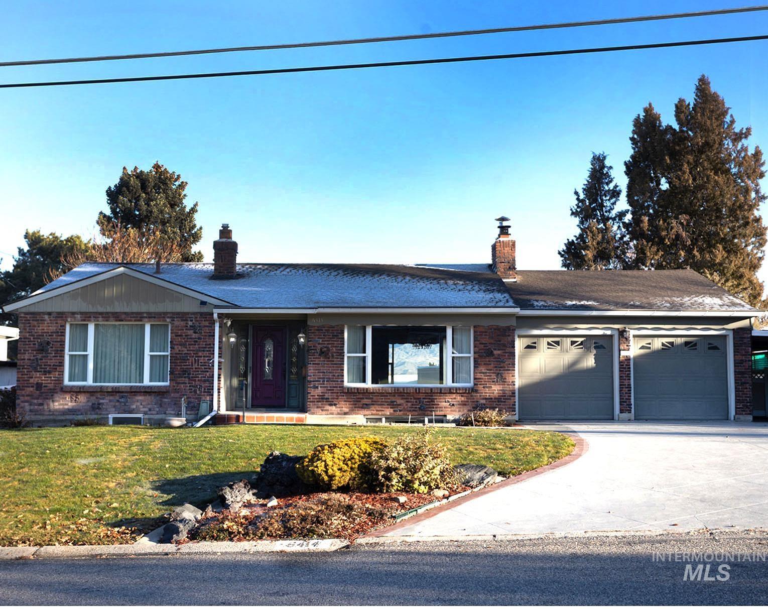 Ranch-style house with a chimney, a front yard, brick siding, and driveway