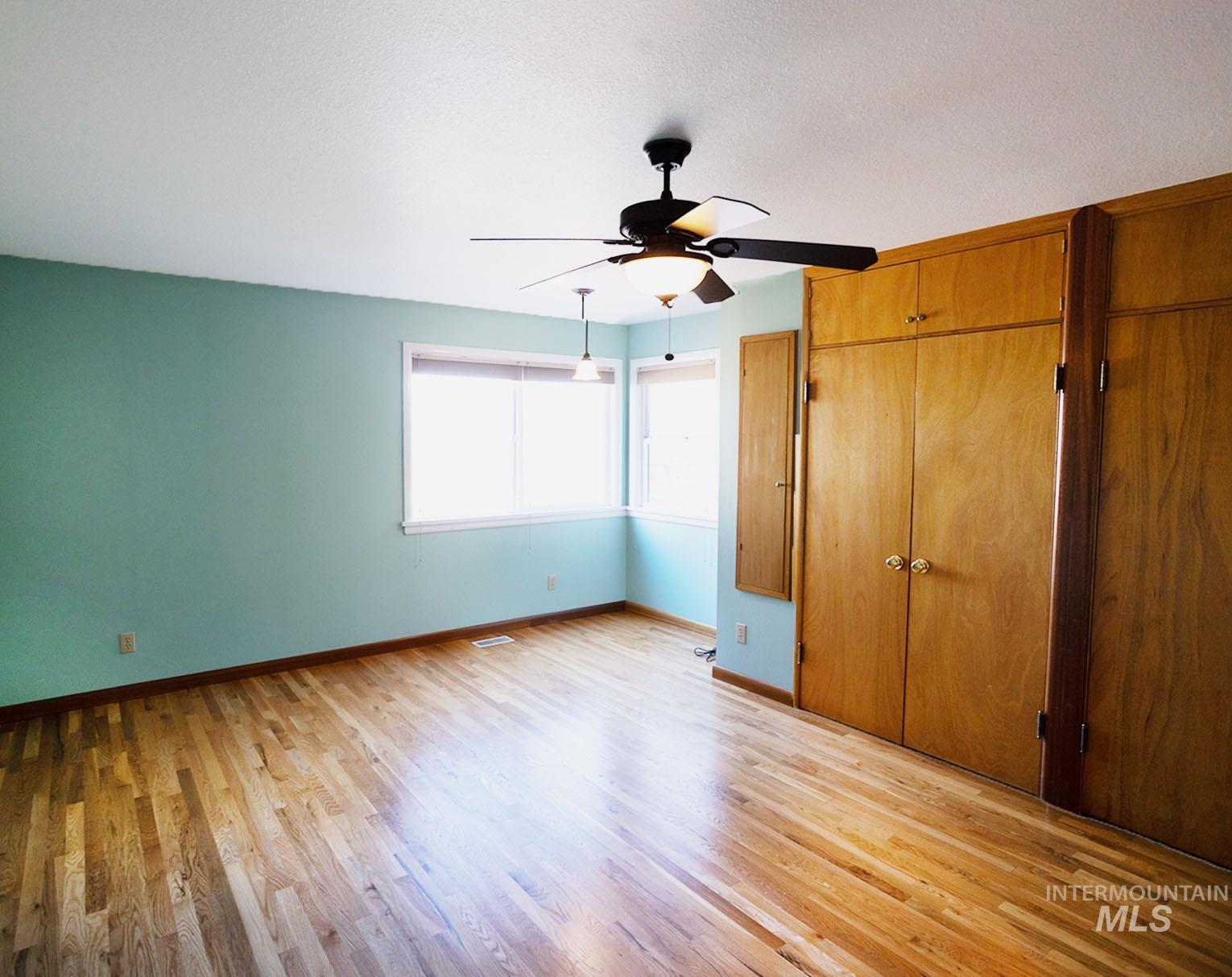 Unfurnished bedroom with a closet, light wood-style flooring, ceiling fan, and a textured ceiling