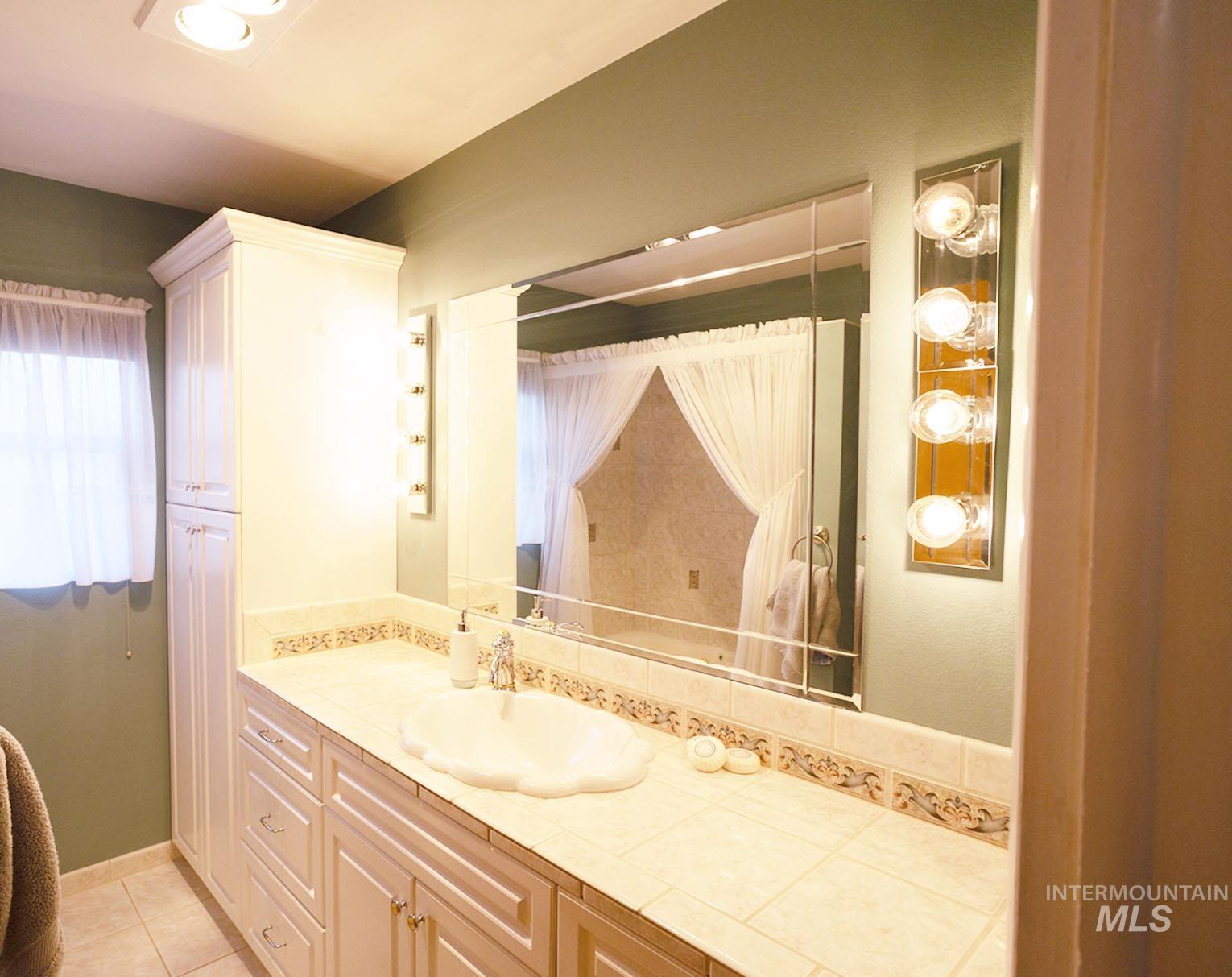 Bathroom with vanity, a shower with shower curtain, and light tile patterned flooring