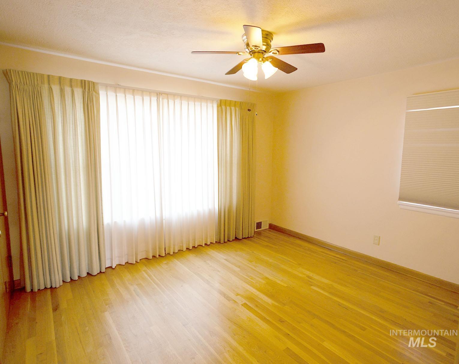Spare room with light wood-style flooring, a textured ceiling, and ceiling fan