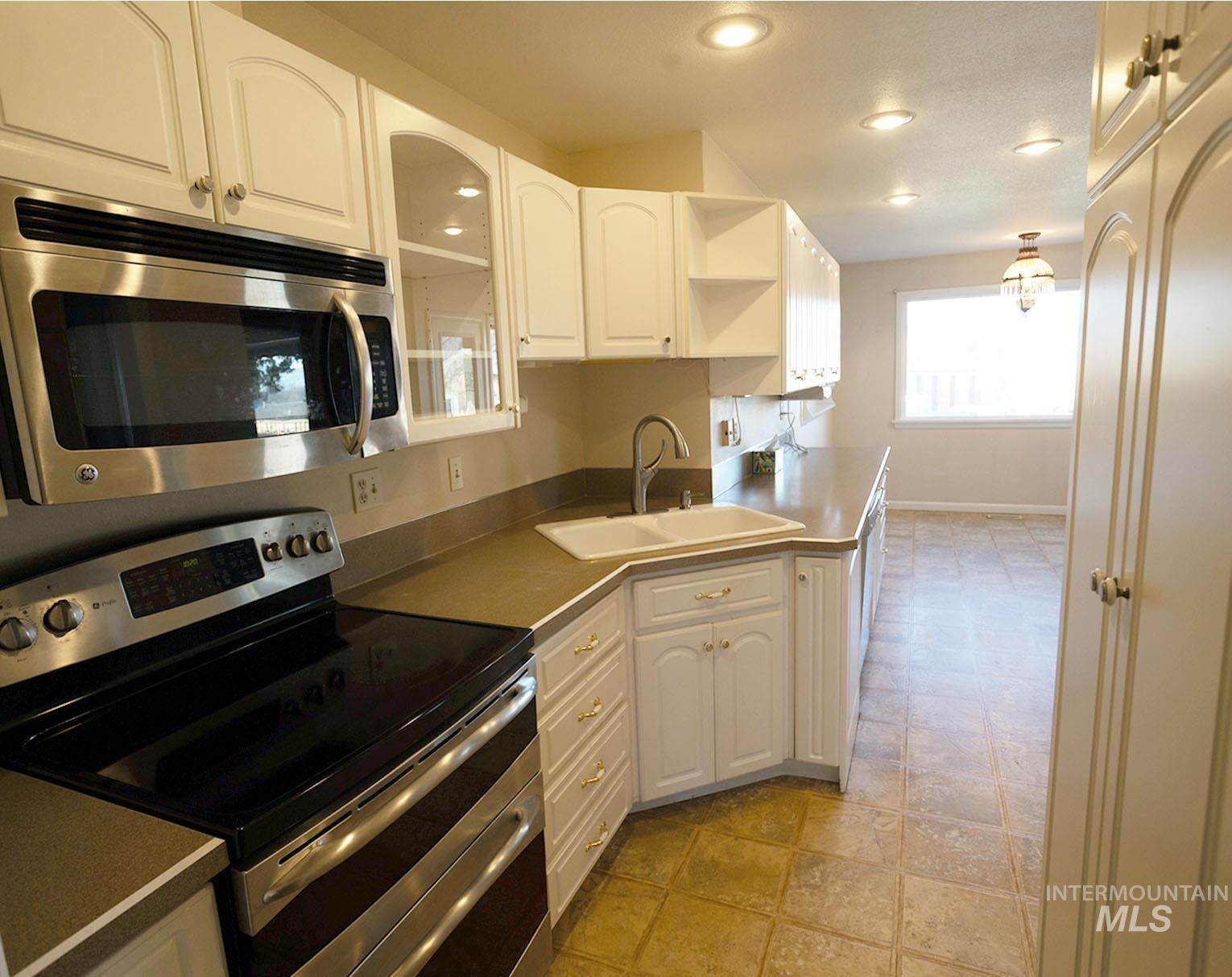 Kitchen featuring appliances with stainless steel finishes, white cabinets, recessed lighting, open shelves, and glass insert cabinets