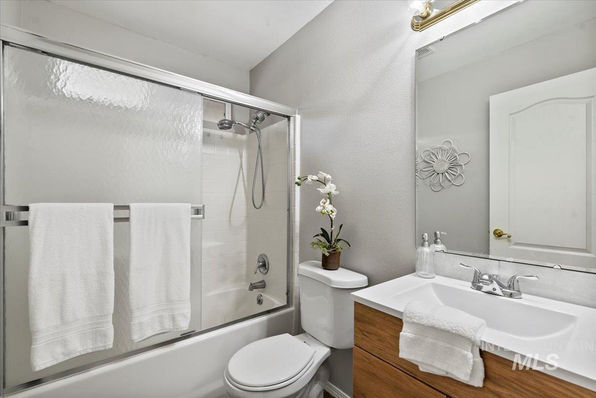 Bathroom featuring vanity, enclosed tub / shower combo, and a textured wall
