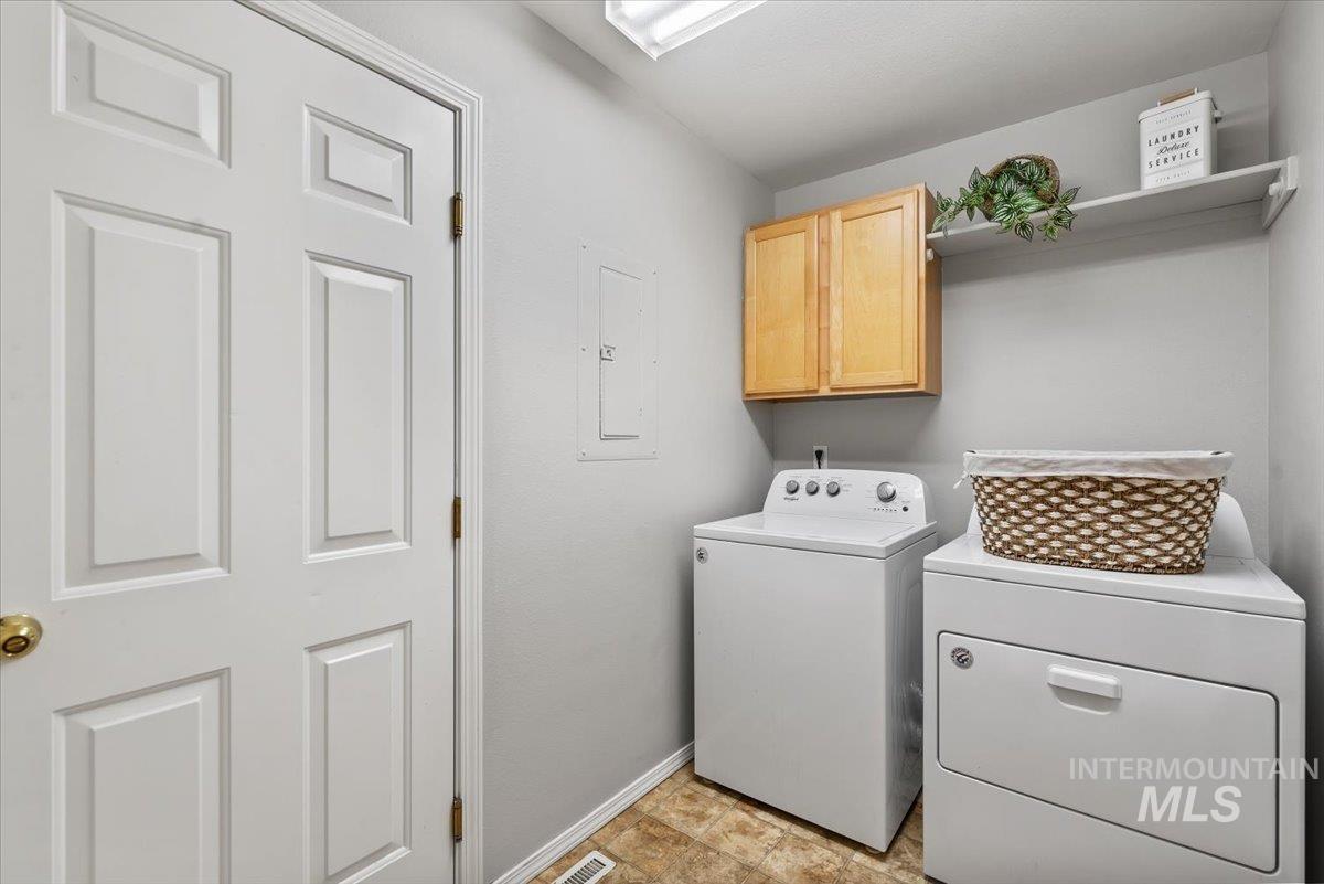 Laundry room with cabinet space, electric panel, and separate washer and dryer