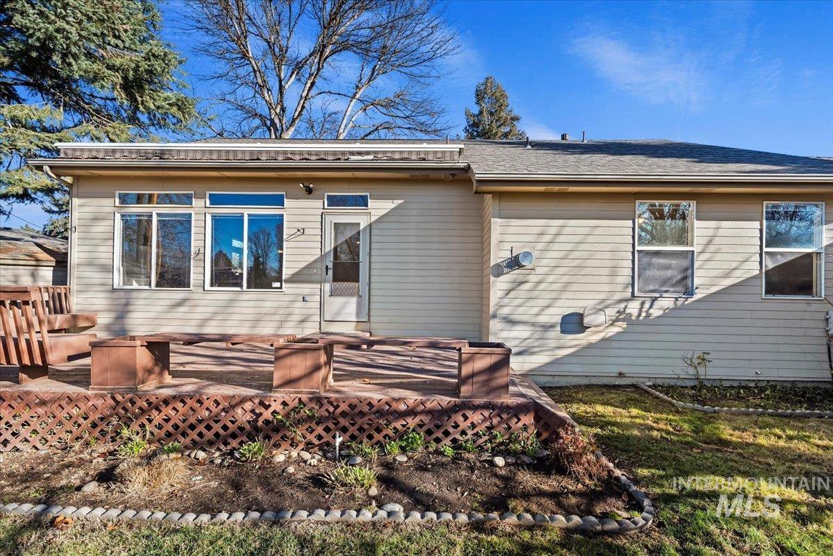 Rear view of house with a wooden deck and a shingled roof