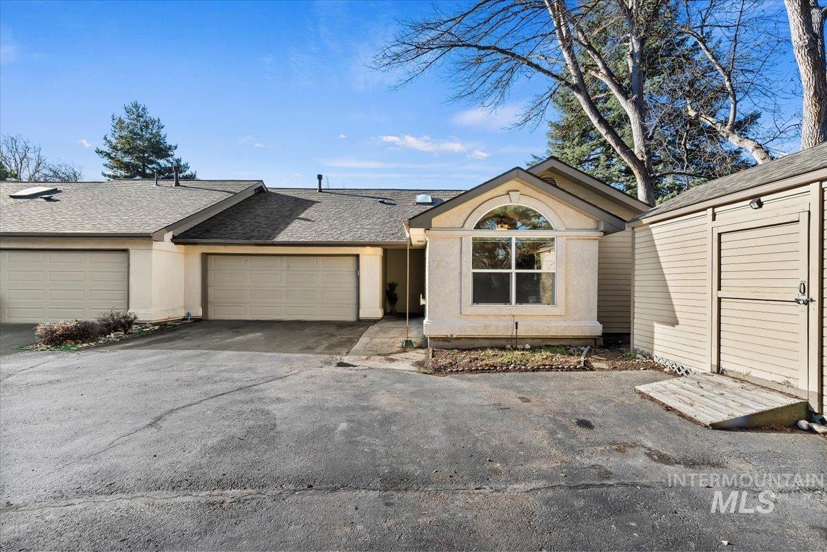 Single story home with roof with shingles, a storage unit, driveway, and a garage