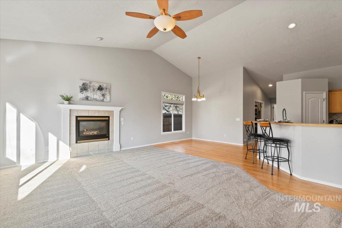 Living area with a fireplace, recessed lighting, high vaulted ceiling, a ceiling fan, and light wood-style flooring