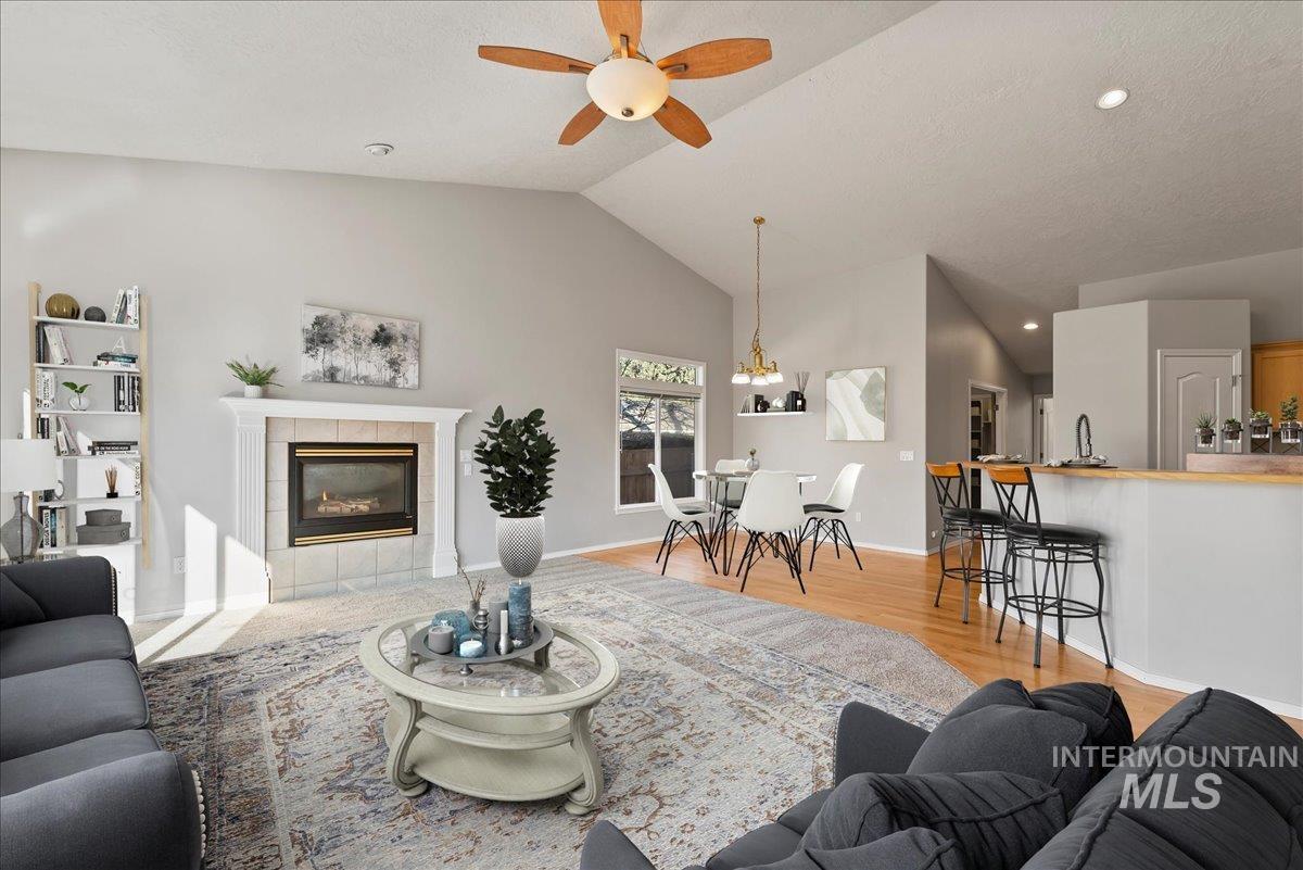 Living room with a tile fireplace, light wood-style floors, lofted ceiling, recessed lighting, and ceiling fan