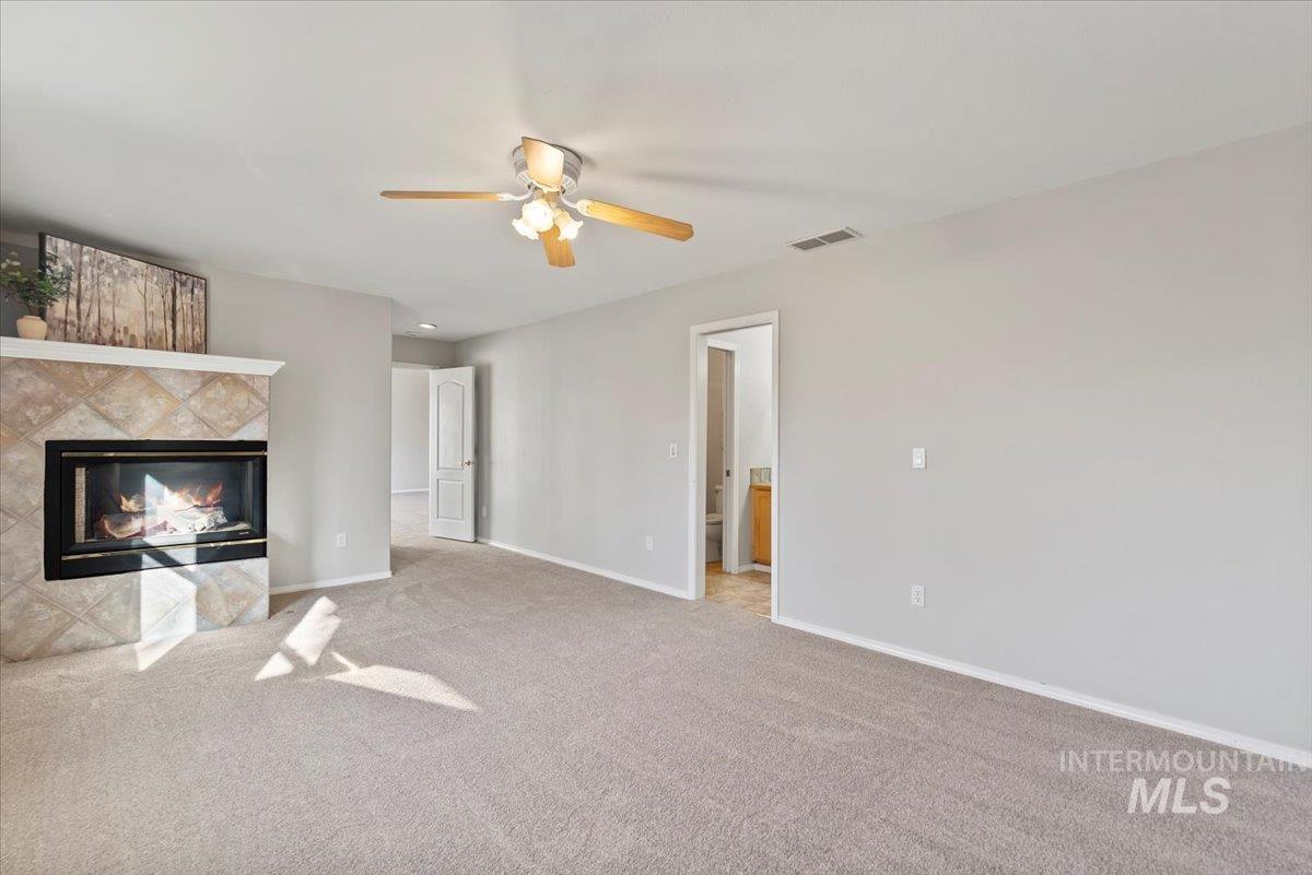 Unfurnished living room with carpet flooring, a fireplace, and a ceiling fan