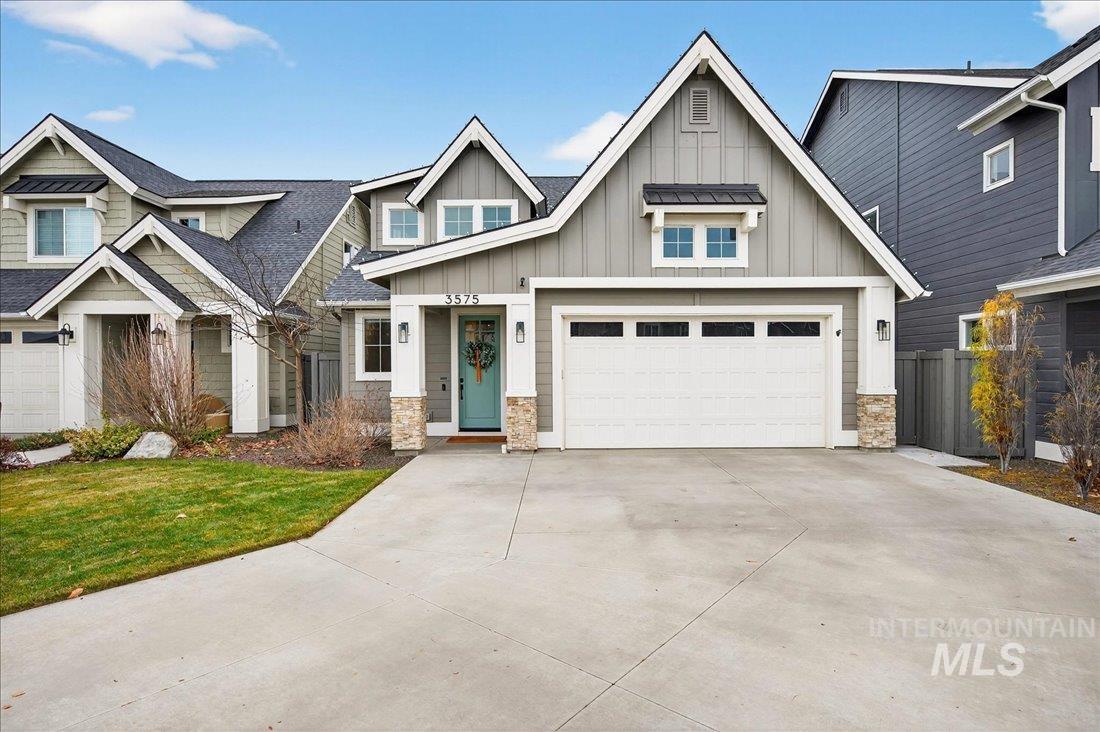 Craftsman house featuring board and batten siding, stone siding, driveway, and roof with shingles