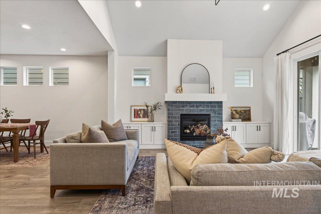 Living room with a fireplace, wood finished floors, recessed lighting, and vaulted ceiling