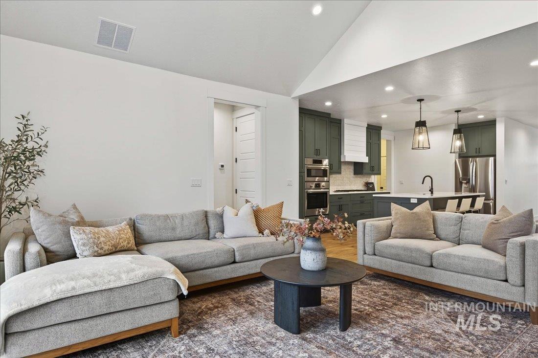 Living room featuring dark wood-style flooring, high vaulted ceiling, and recessed lighting