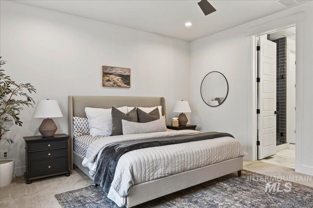 Bedroom featuring light colored carpet, ensuite bathroom, and ceiling fan