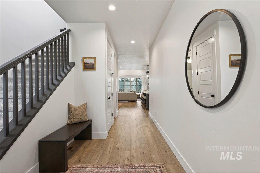 Hall featuring light wood-type flooring, recessed lighting, and stairs