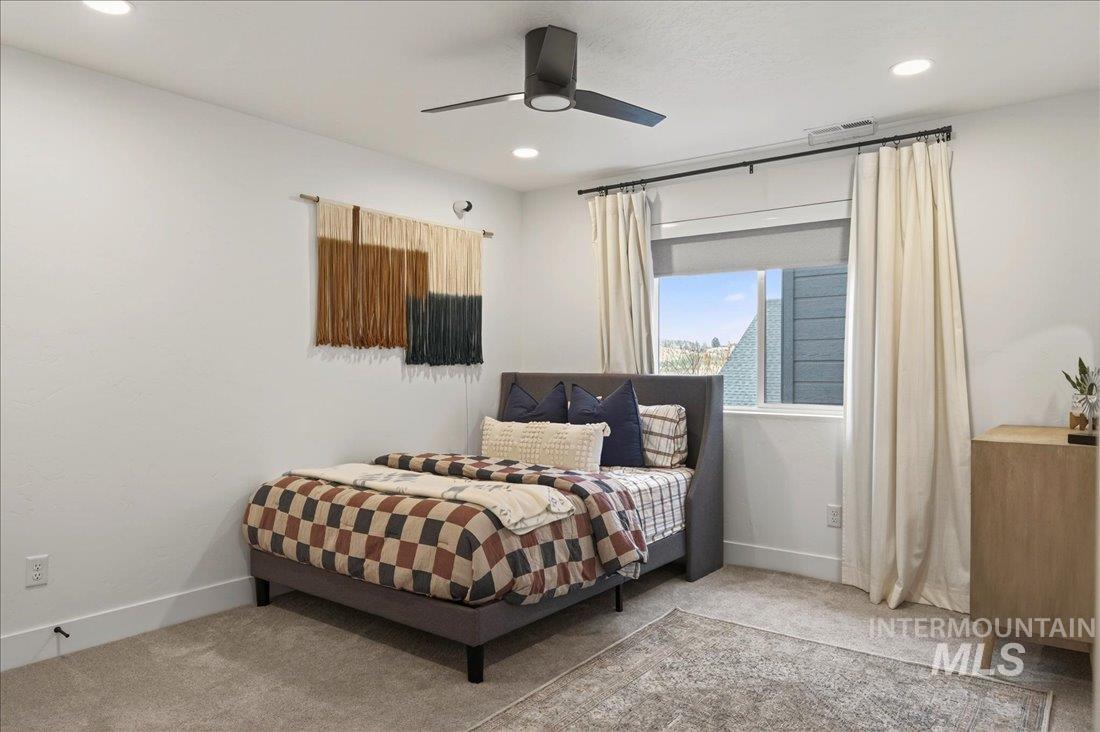 Carpeted bedroom with ceiling fan and recessed lighting