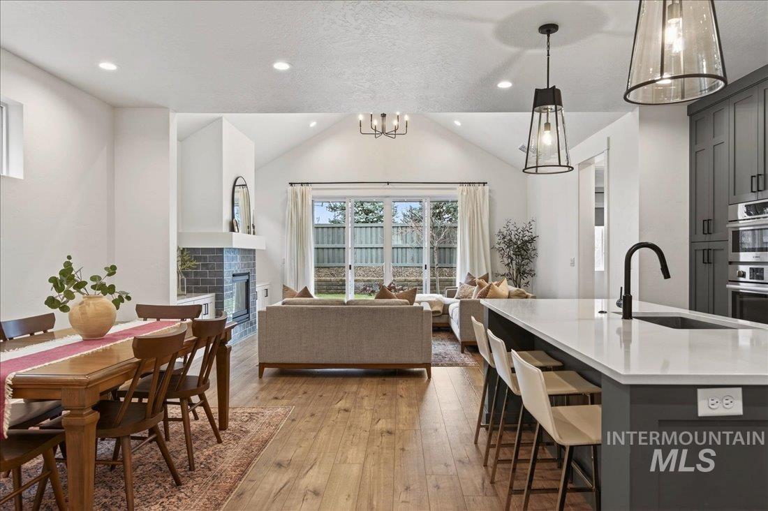 Kitchen featuring gray cabinetry, vaulted ceiling, a glass covered fireplace, light wood finished floors, and hanging light fixtures