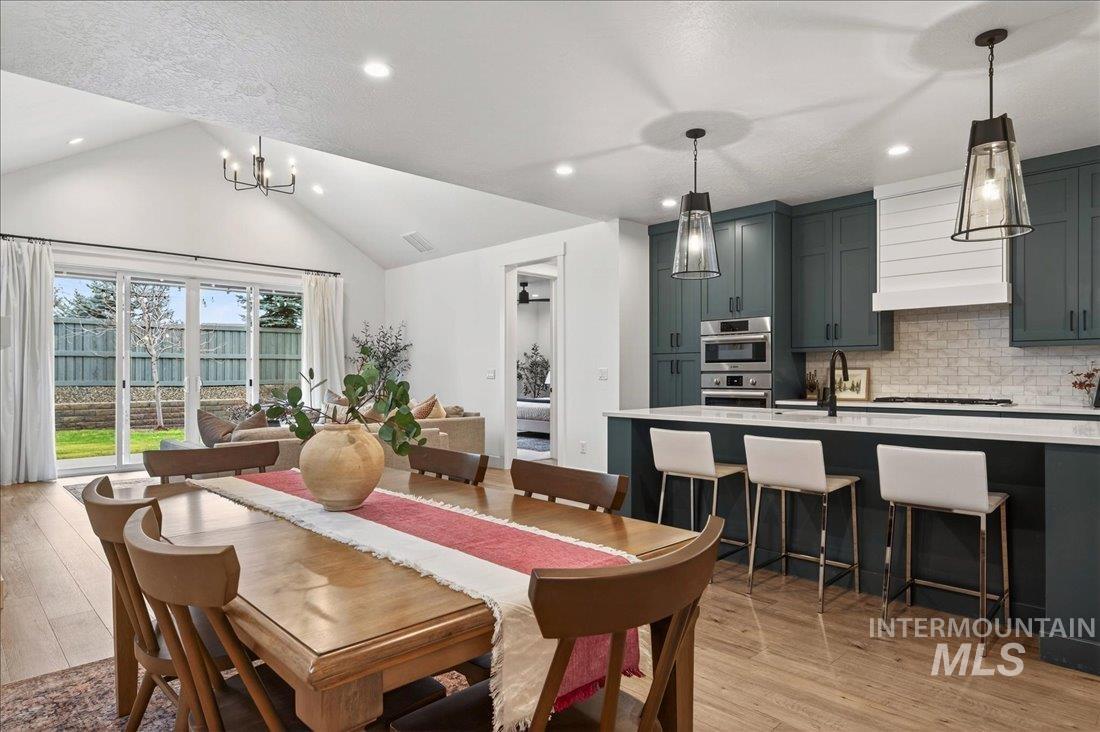Dining area with light wood-type flooring, vaulted ceiling, a chandelier, and recessed lighting