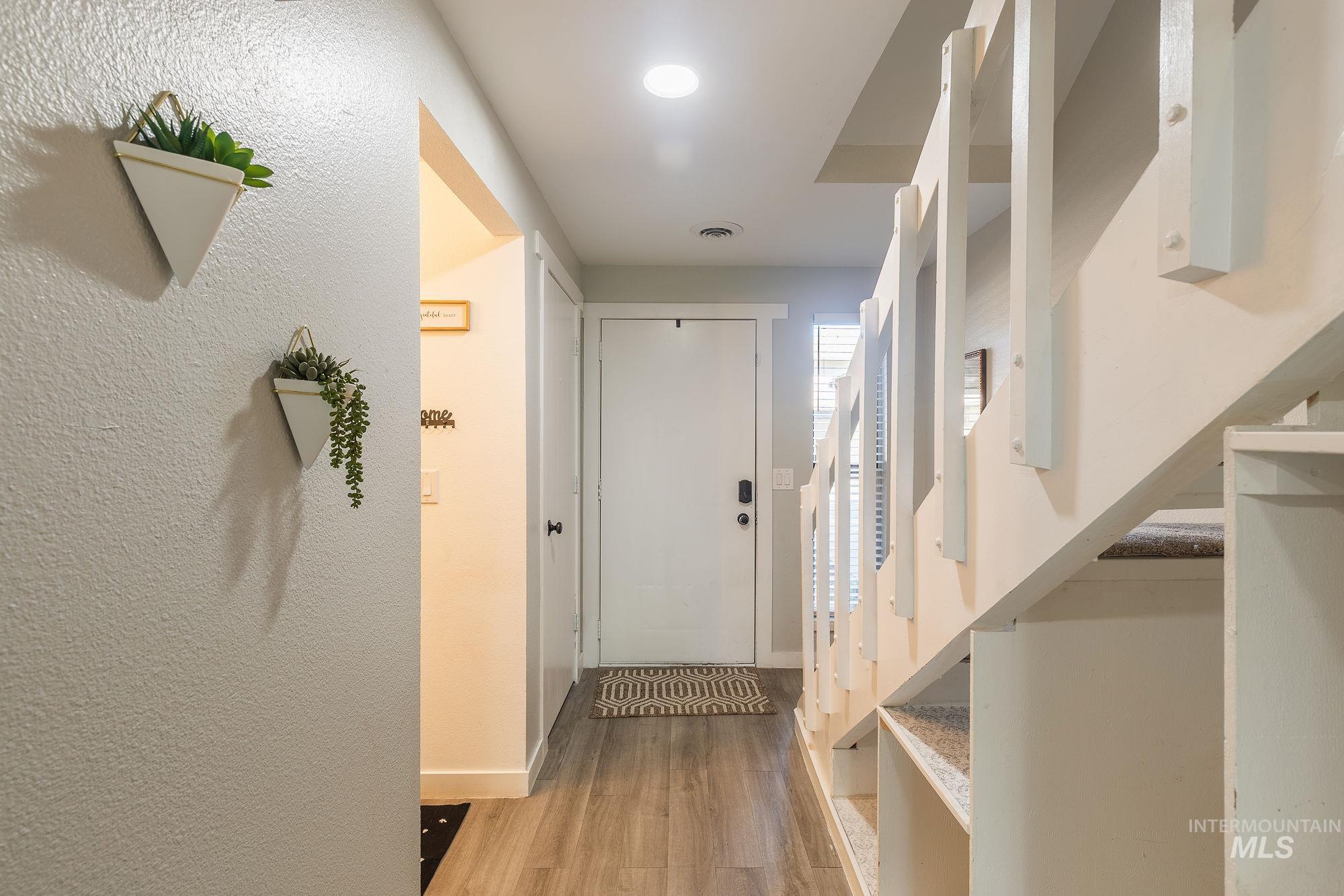 Hall featuring light wood finished floors, stairway, and recessed lighting