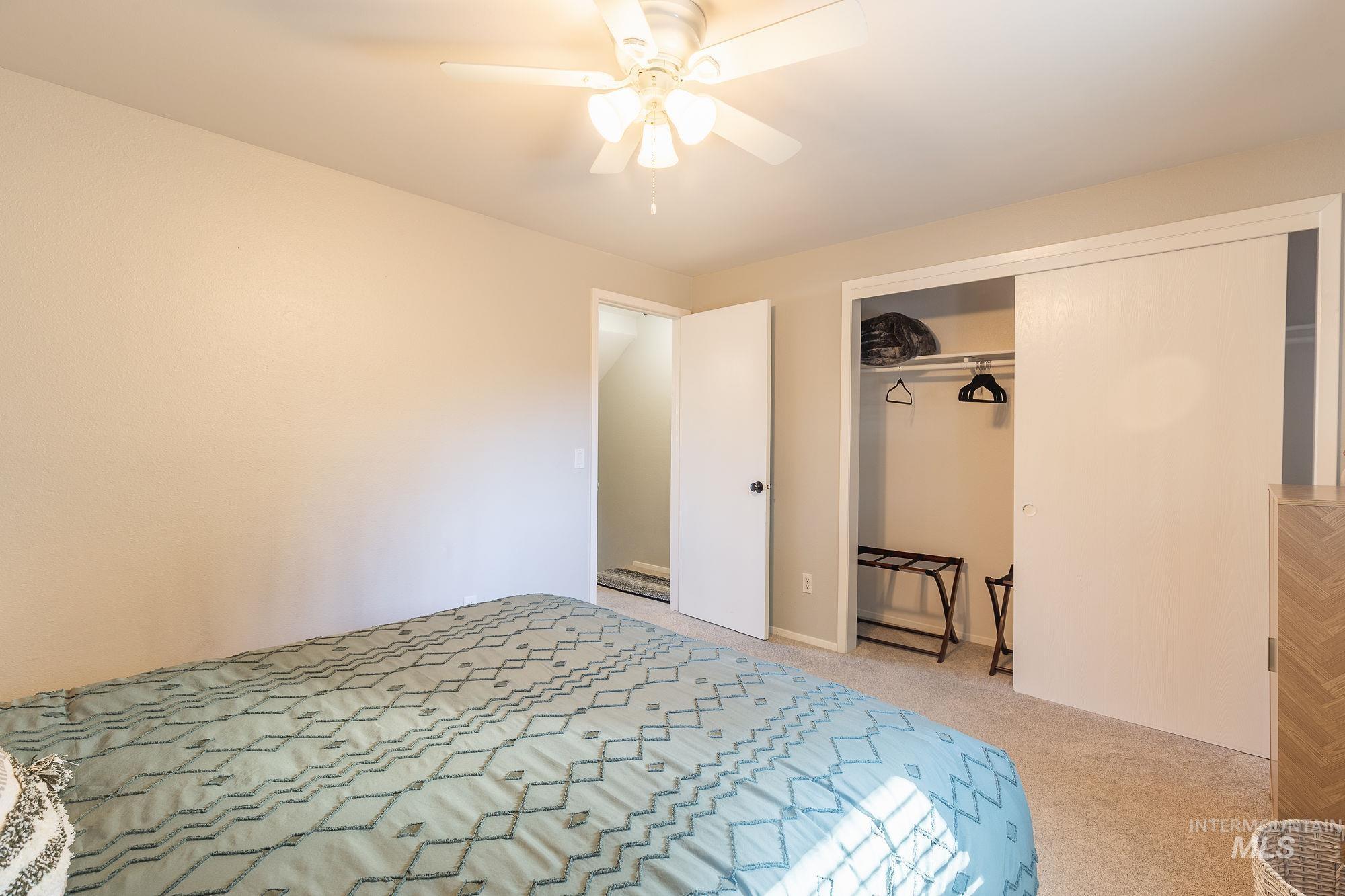 Bedroom with light colored carpet, a closet, and ceiling fan