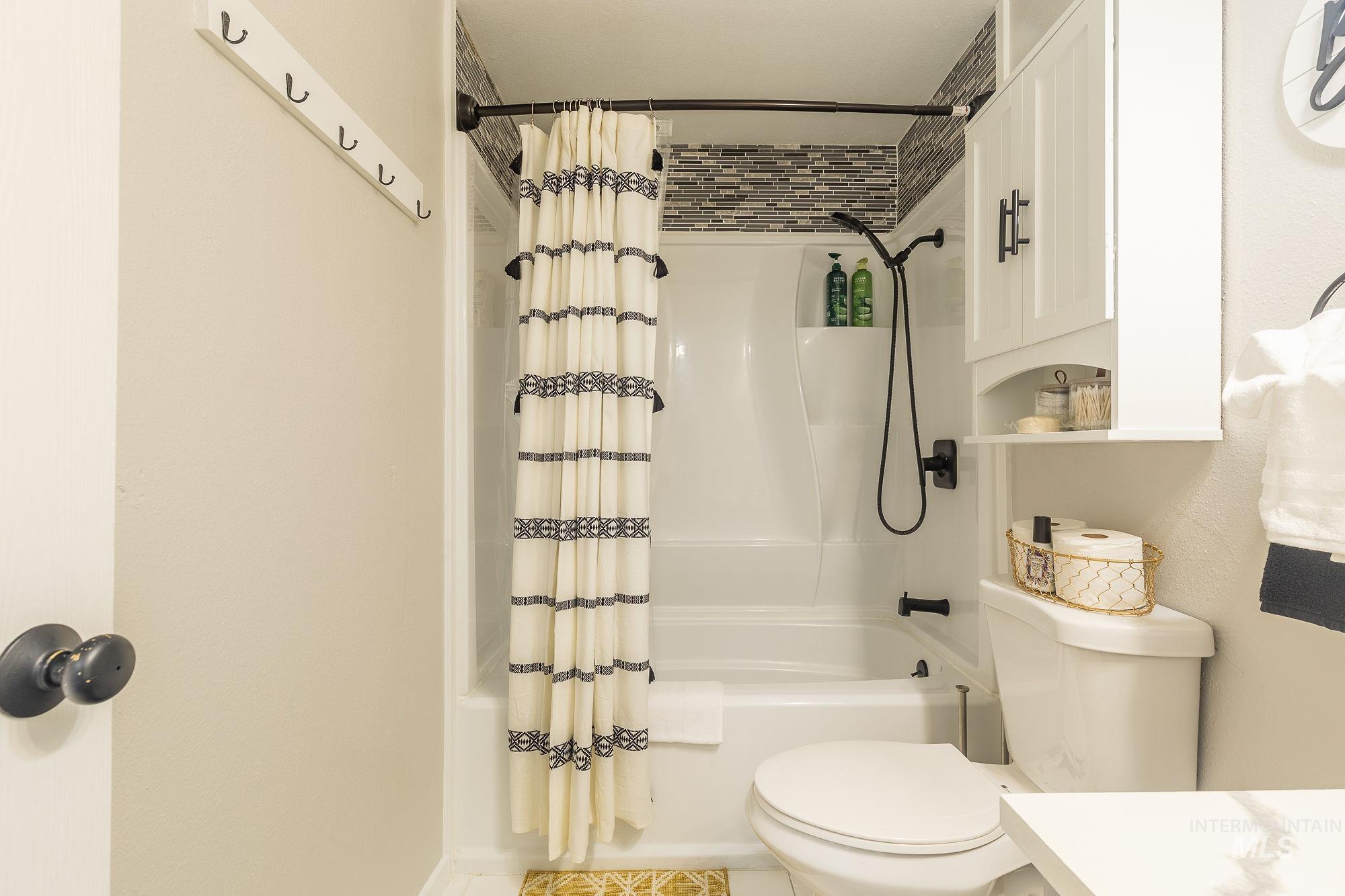 Bathroom featuring shower / bath combo with shower curtain, tile patterned floors, and vanity