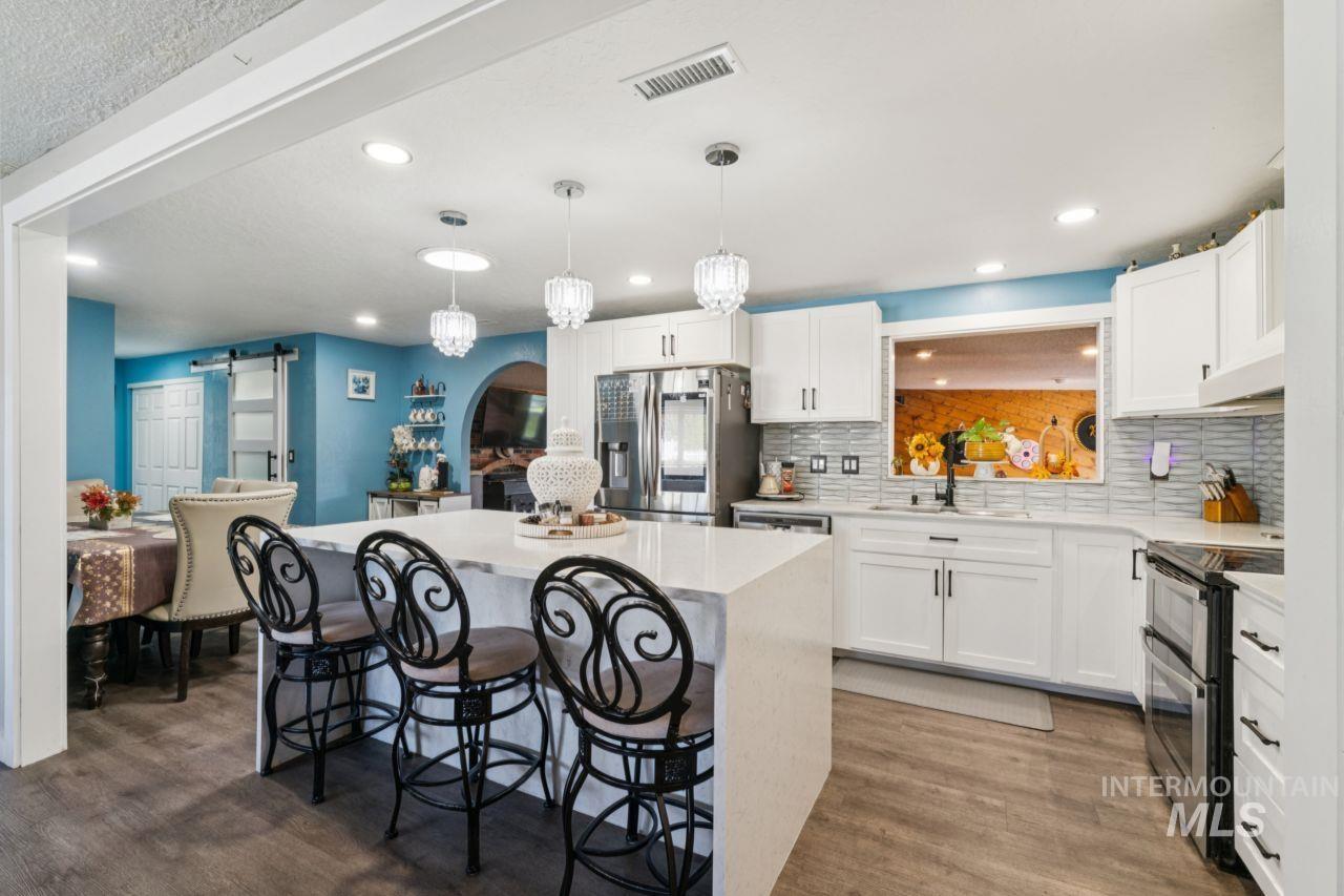 Kitchen with a breakfast bar, a barn door, white cabinets, a kitchen island, and recessed lighting
