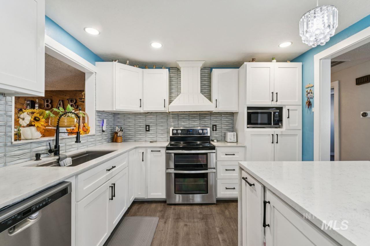 Kitchen featuring stainless steel appliances, tasteful backsplash, white cabinets, custom range hood, and recessed lighting