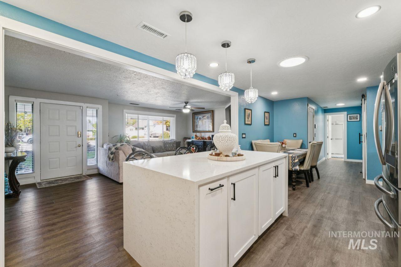 Kitchen featuring white cabinetry, hanging light fixtures, open floor plan, dark wood-style floors, and recessed lighting