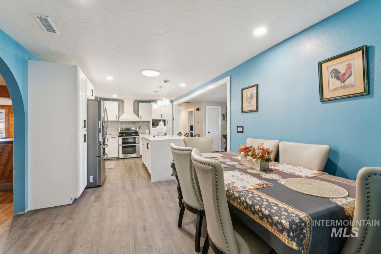 Dining space with arched walkways, light wood-style flooring, a textured ceiling, and recessed lighting