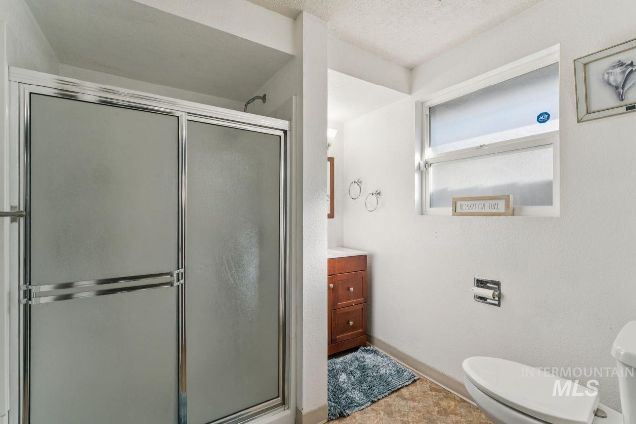Full bath with vanity, a stall shower, and a textured ceiling