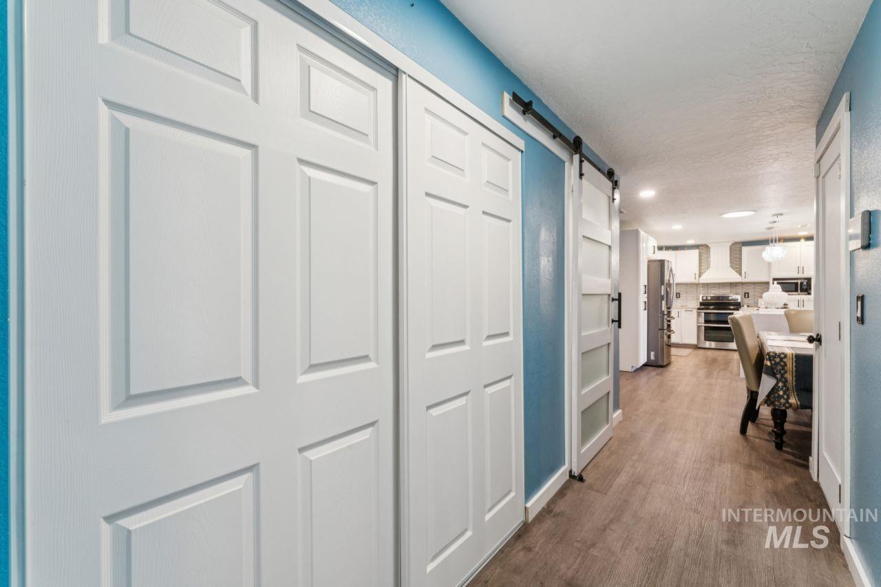 Corridor with a barn door, dark wood-type flooring, and recessed lighting