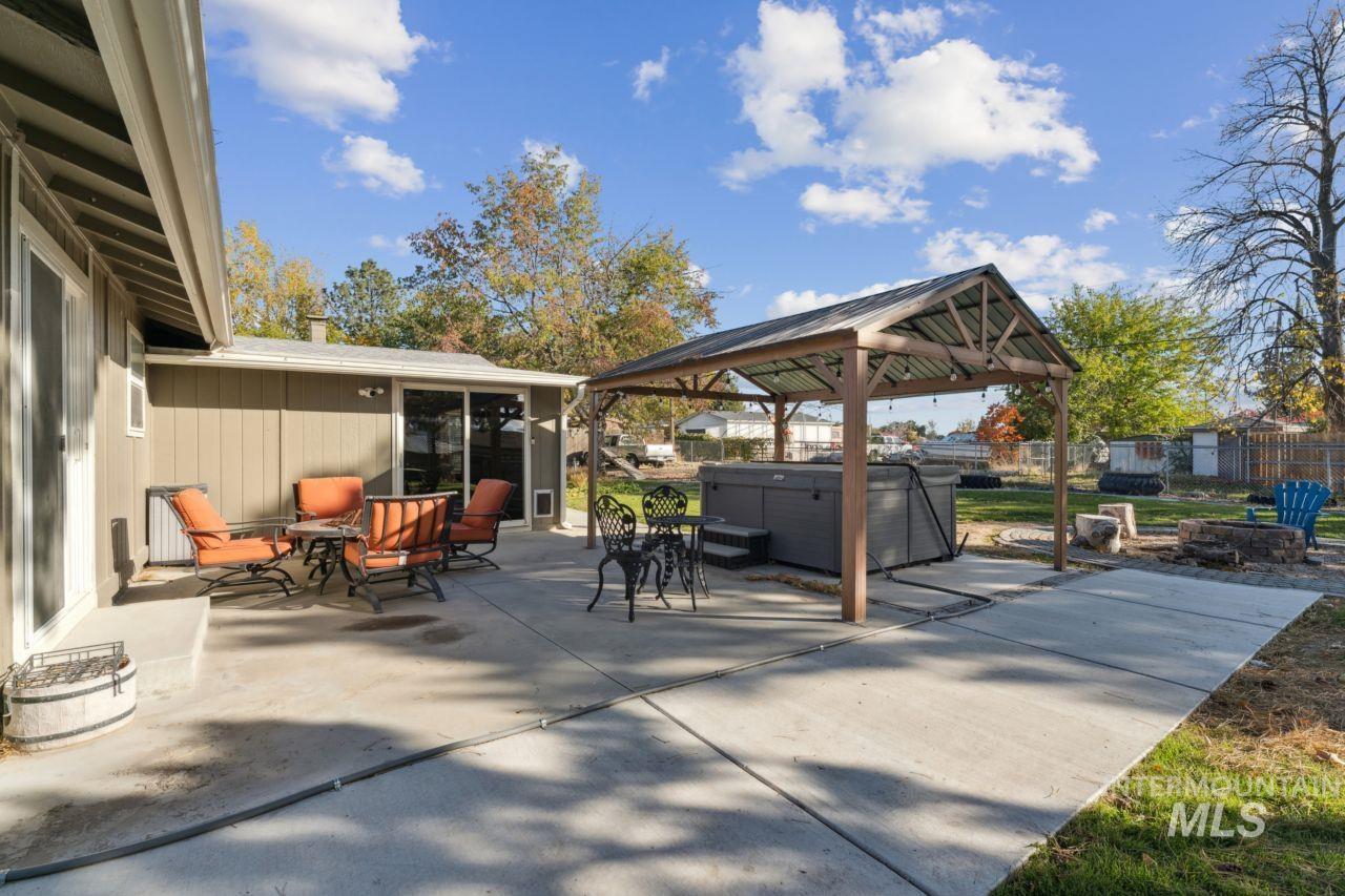 View of patio / terrace with a hot tub, an outdoor fire pit, and a gazebo