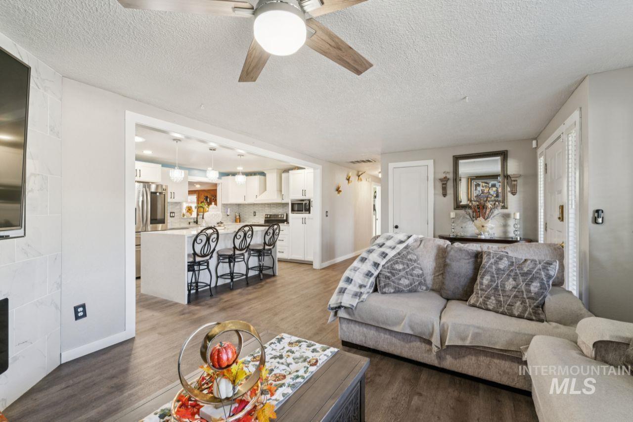 Living room with light wood-style floors, ceiling fan, and a textured ceiling