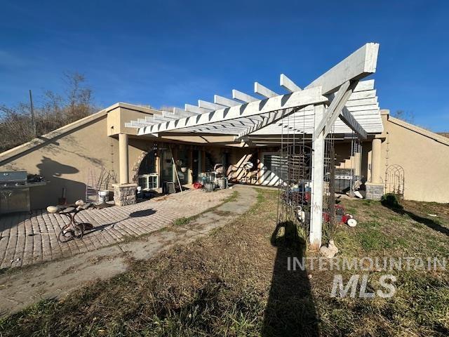 Rear view of property with a pergola, a patio area, and stucco siding