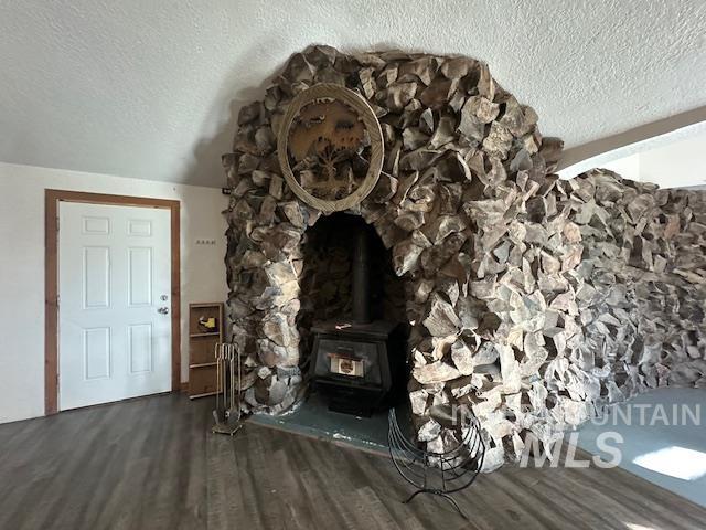Living area with a wood stove, a textured ceiling, and dark wood-style floors