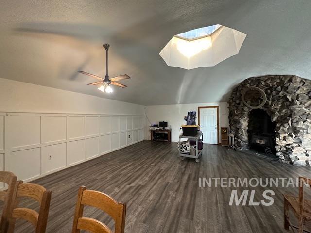 Bonus room with a wood stove, vaulted ceiling, dark wood-style floors, a decorative wall, and ceiling fan
